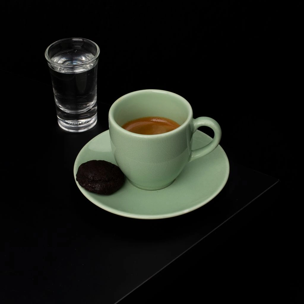 A dark chocolate espresso cookie beside two espresso beans.